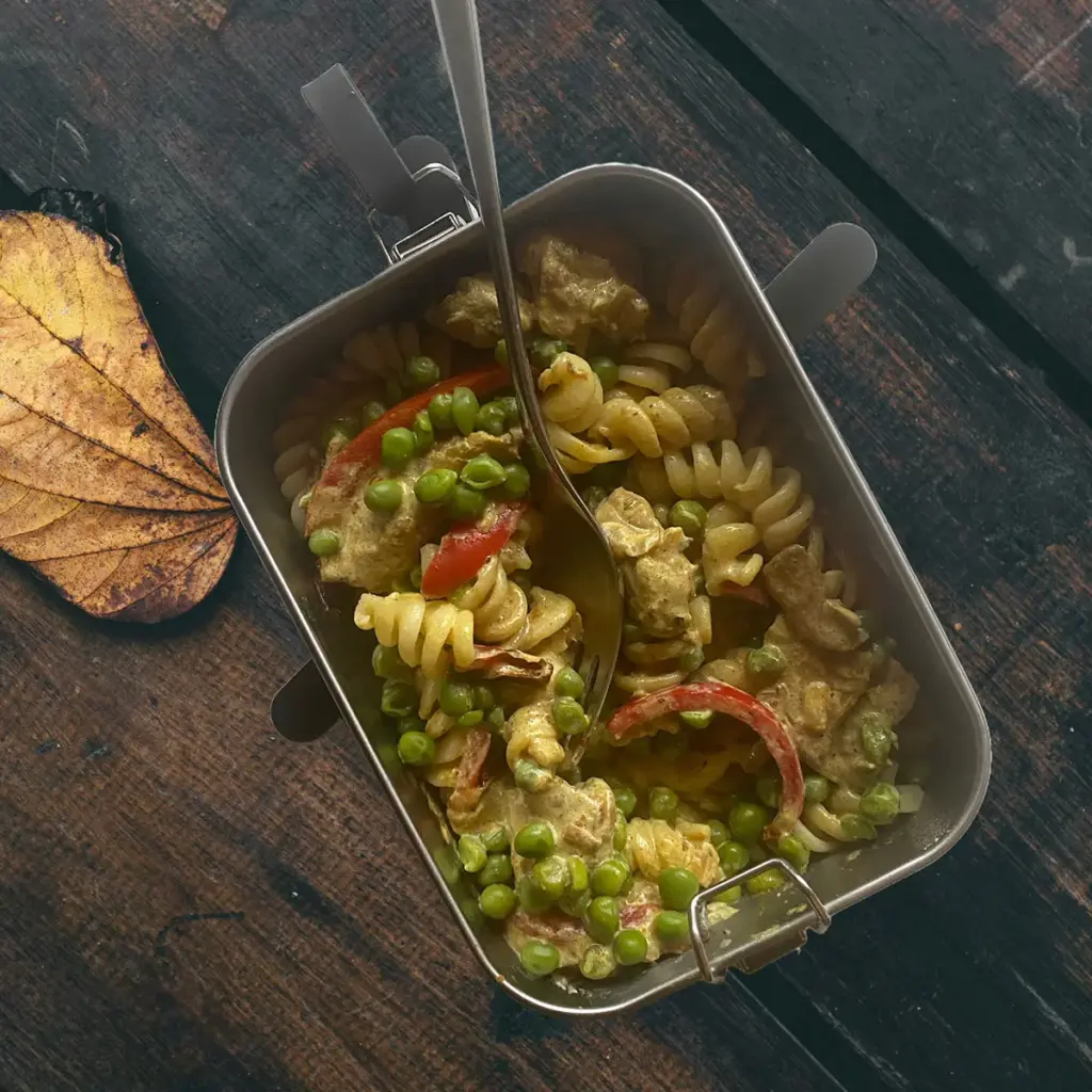 Freshly heated pasta with vegetables in the PREMIUM lunchbox from HEAT.me on an old wooden table with autumn leaves