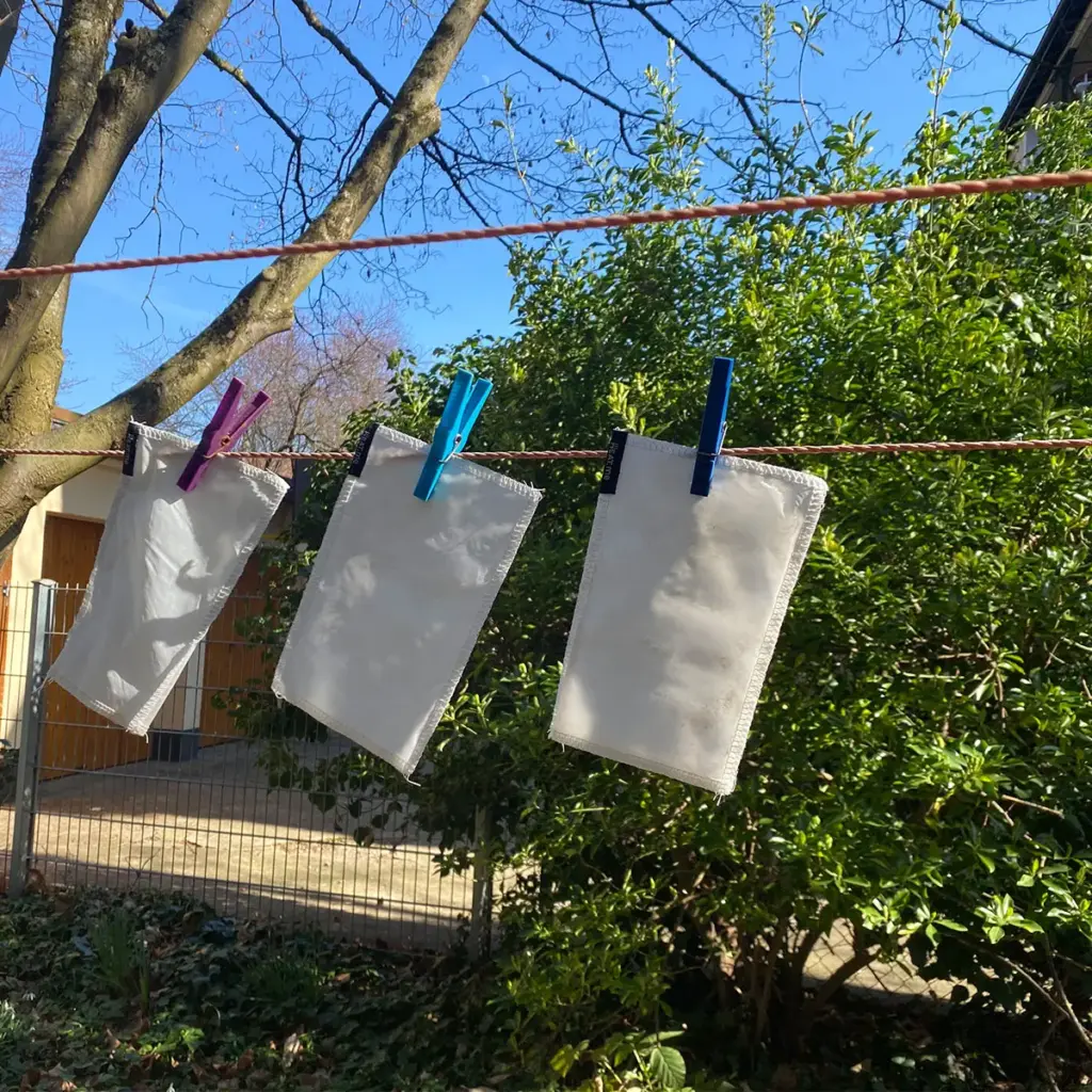 Three protective covers hang on a washing line to dry - after being washed at 30°C in the washing machine.